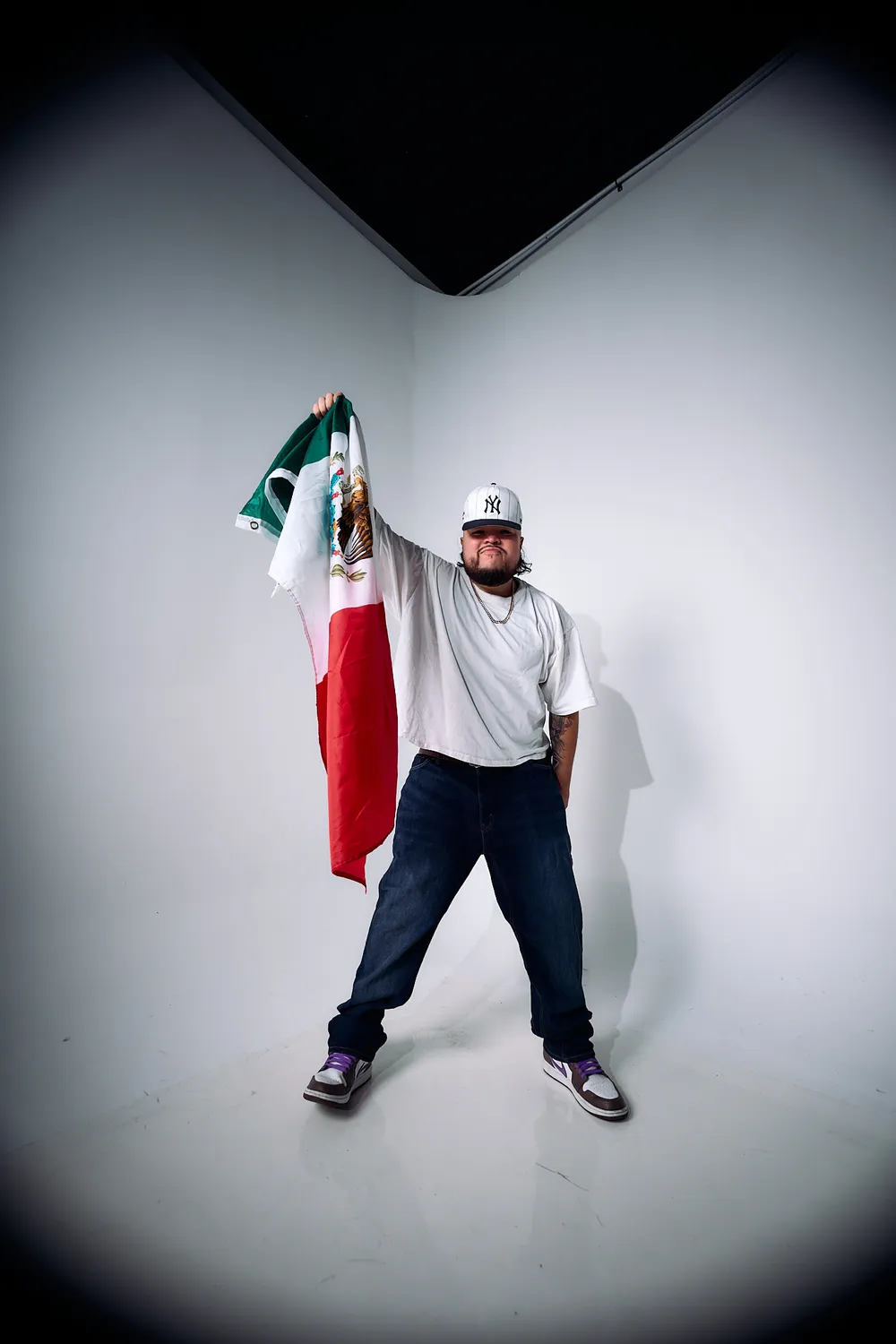 Papi AQ raising the Mexican flag in a spotlight.