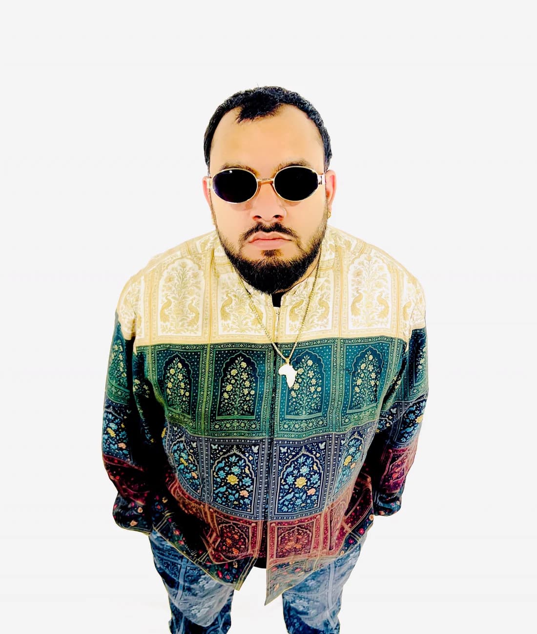 Sylus Rose in round gold sunglasses and a patterned jacket.